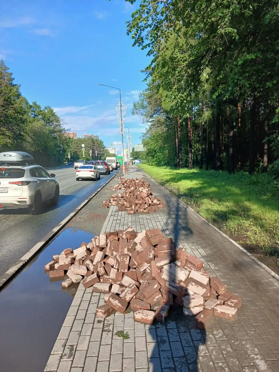На улице Худякова обновляют красную полосу для велосипедистов в лесной зоне — при том, что пешеходов почти нет, а столбы освещения стоят прямо на новом покрытии.